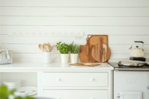 Stylish kitchen counter with herb pots, cutting boards, and utensils against a white backdrop.