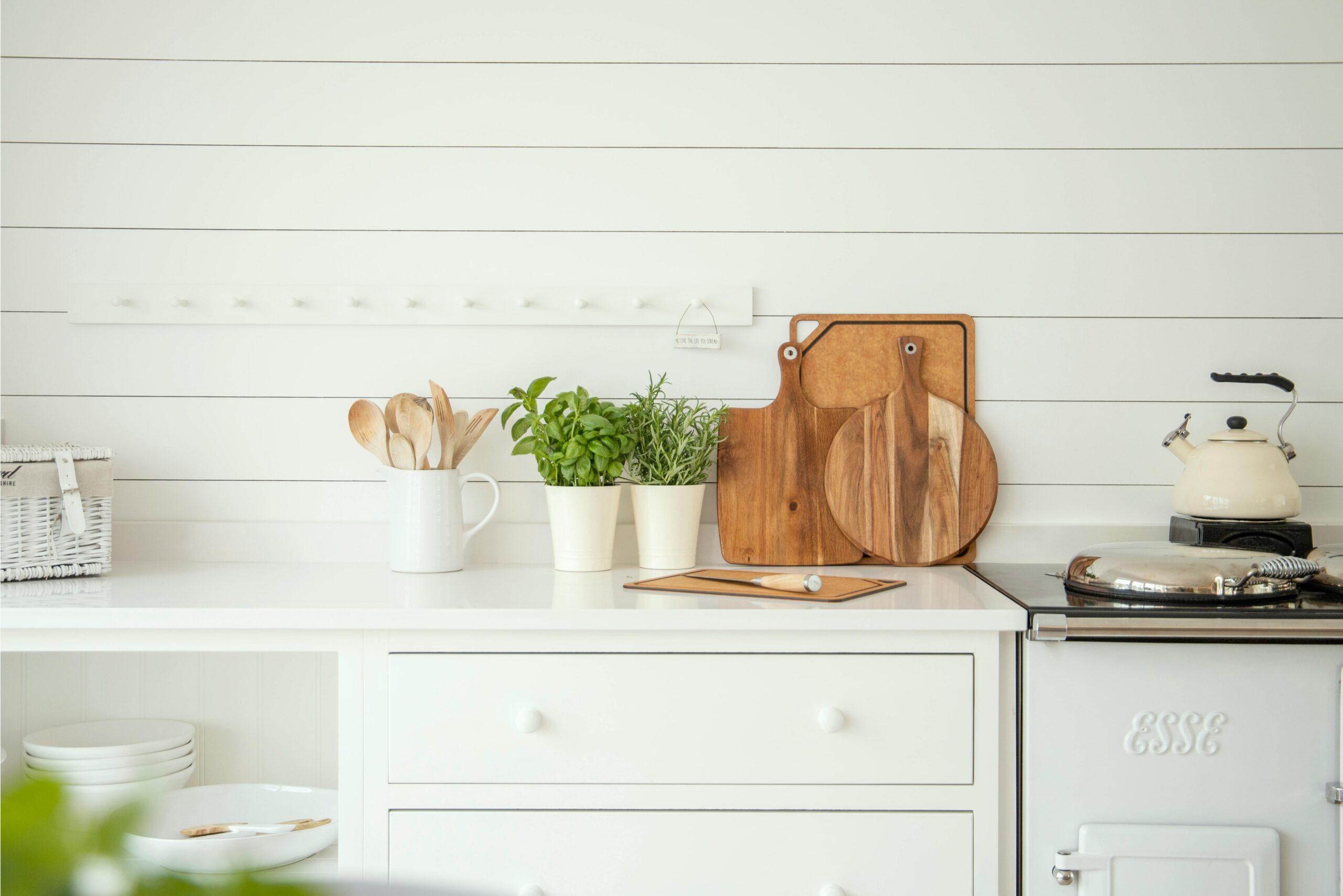 Stylish kitchen counter with herb pots, cutting boards, and utensils against a white backdrop.